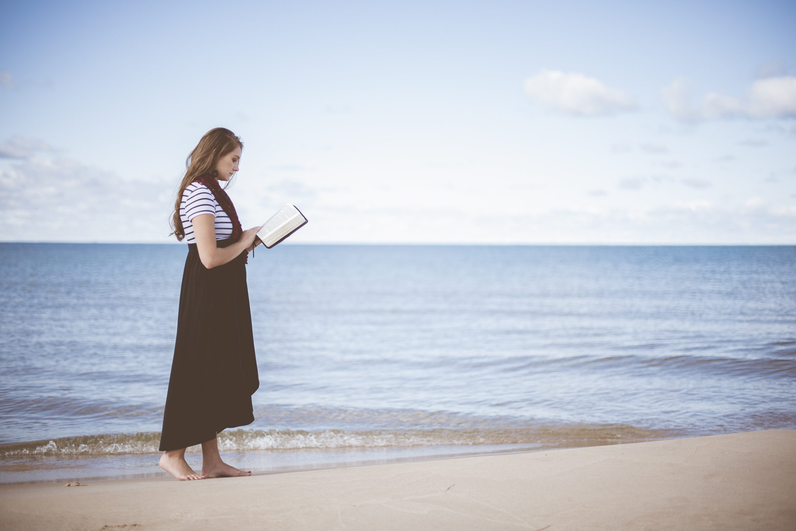 Una chica leyendo un libro de comedia romántica en la playa durante el verano.